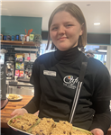 Photo of Grace the intern at Mission Employable holding a plate of flapjack