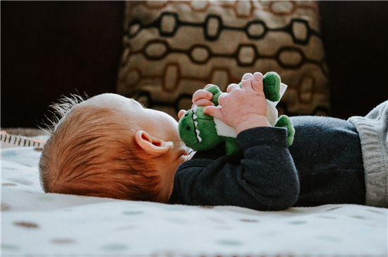 image of baby laying down with stuffed toy in hand