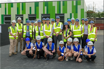 students, staff, contractors all posing for a photo at site of new building