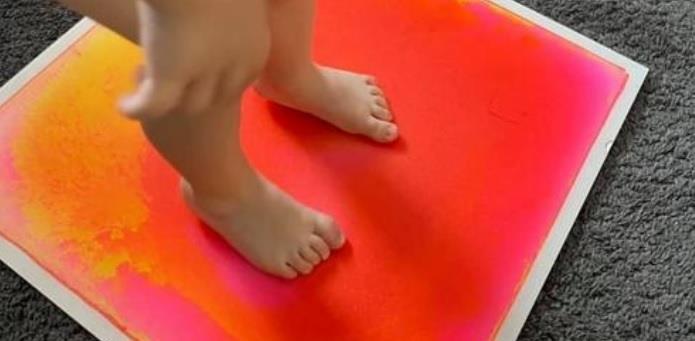 A child standing on a sensory colour changing tile