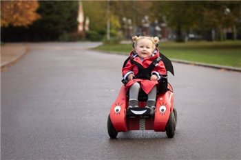 Young child in a \'wizzibug\' on a footpath