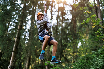 boy on zip line in the woods