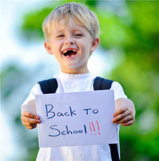 Young boy smiling and holding sign saying back to school